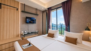 A hotel room with a bed, a TV mounted on the wall, a window with curtains, and a city view. - Stellar Living Studio At Sky House Bsd (Pagedangan)