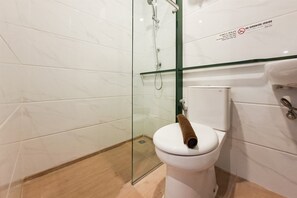 Ein modernes Badezimmer mit Duschkabine aus Glas, einer weißen Toilette und einem Waschtisch mit Glasplatte.