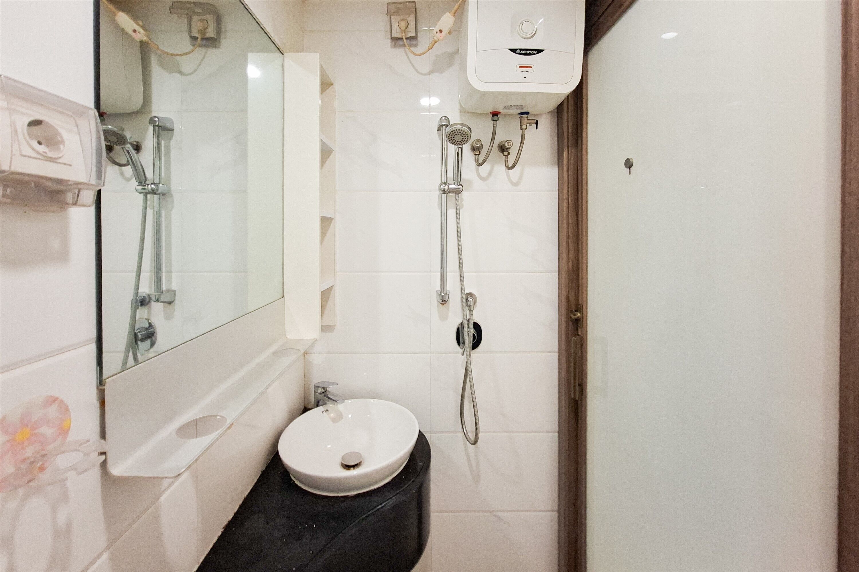 A bathroom with a white sink, a mirror, a shower with a handheld showerhead, and a toilet.