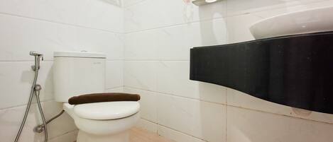 A bathroom with a toilet, a shower, and a black sink.
