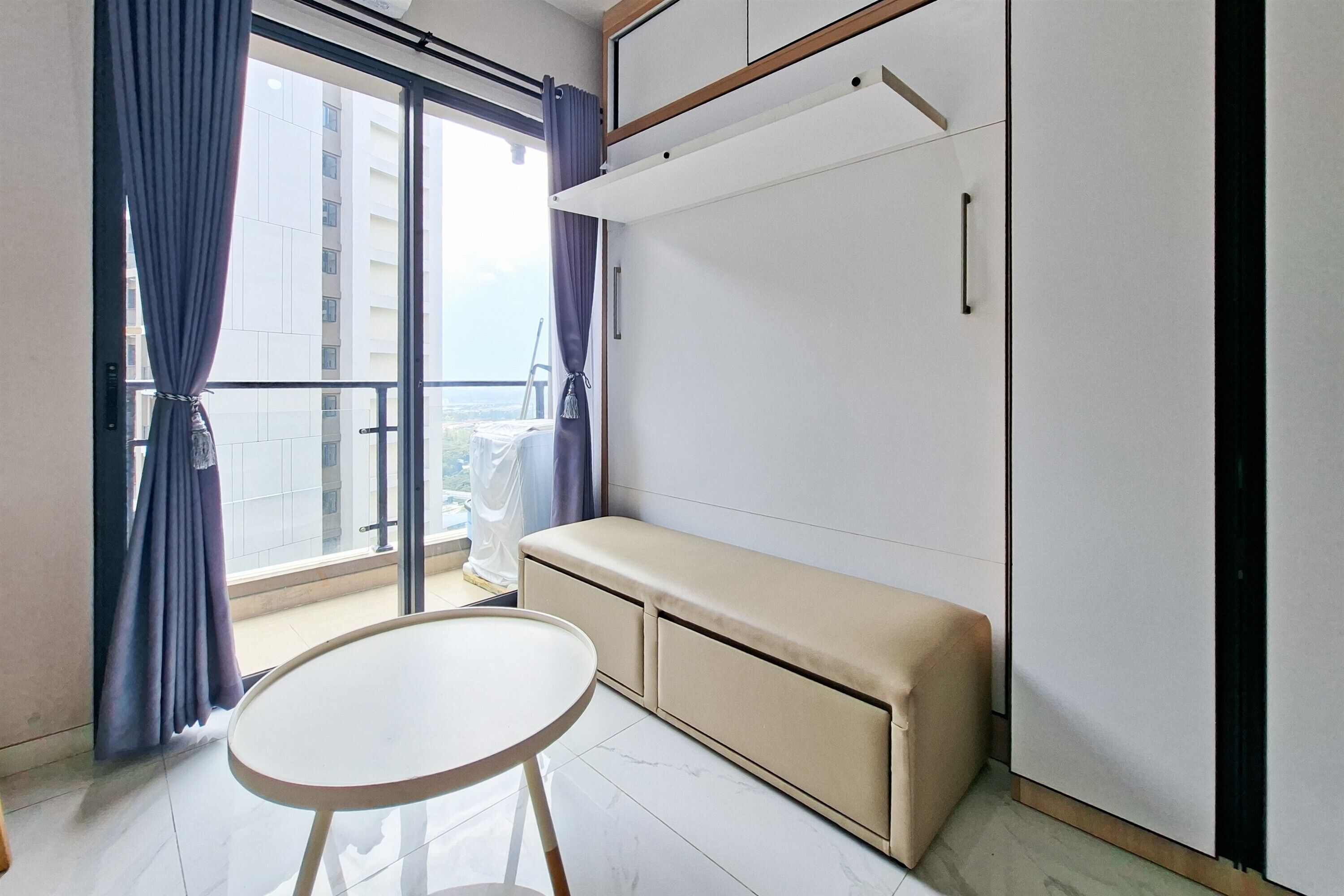 A room with a sliding glass door, a bench, a small table, and a wardrobe.