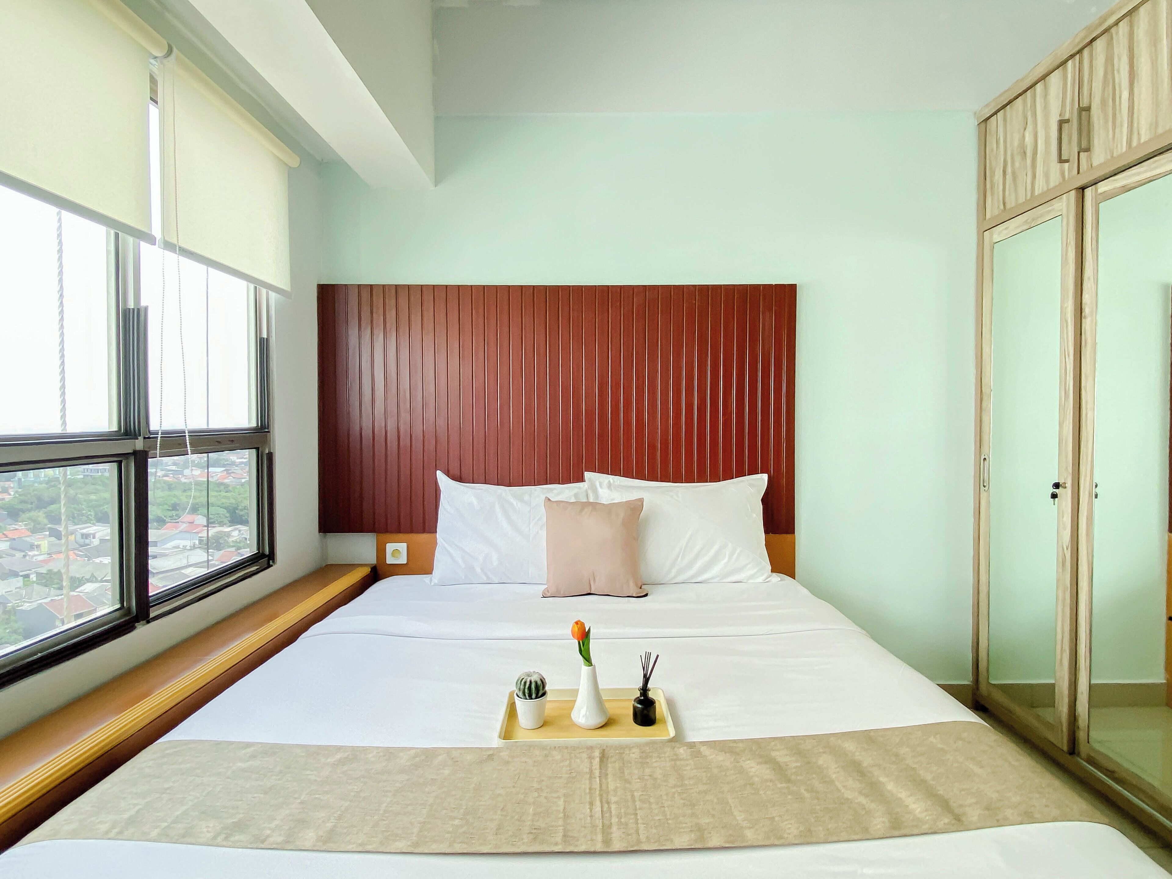 A hotel room with a large bed, a wooden headboard, a window with a view, and a wardrobe.