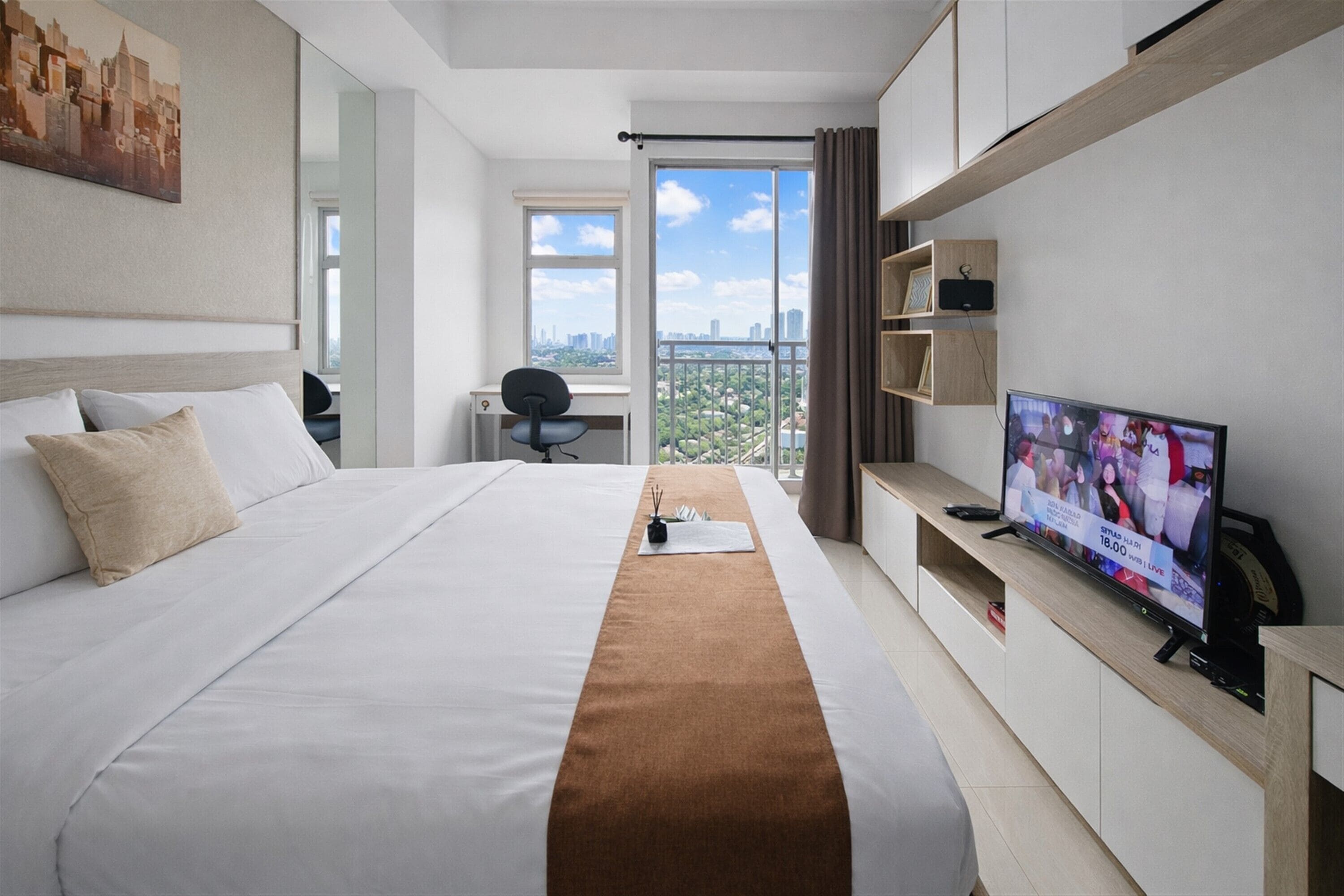 Ein Hotelzimmer mit einem großen Bett, einem Schreibtisch, einem Fernseher und Blick auf die Stadt.