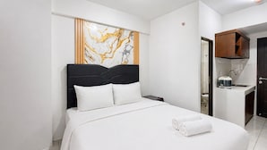 Ein Hotelzimmer mit Bett, Nachttisch, Bad und einer Küchenzeile.
