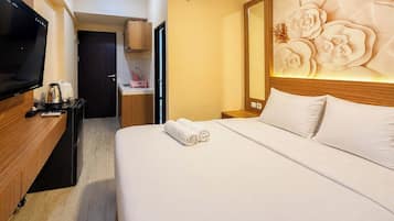 Habitación de hotel con cama, televisor, escritorio de madera, mesita de noche y pared con diseño floral.