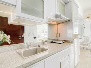 A modern kitchen with a granite countertop, stainless steel sink, and white cabinetry. - Minimalist And Homey Studio Apartment Taman Melati Margonda (Depok)
