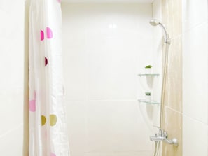 Ein Badezimmer mit Dusche, einer Glasablage mit Pflanzen und einer weißen Fliesenwand.