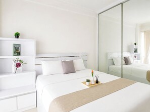 Ein Hotelzimmer mit Bett, Nachttischen, einem Spiegel und einem Regal mit Büchern und einer Pflanze.