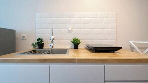 Una cuina moderna amb taulell de fusta, una aixeta d'acer inoxidable i dues plantes en test.