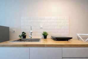 Eine moderne Küche mit einer Holz Arbeitsplatte, einem Edelstahl-Spülbecken und zwei Topfpflanzen.