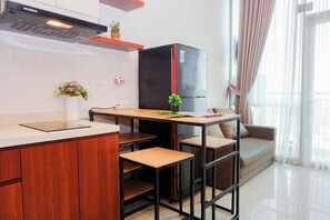 Eine moderne Küche mit einem schwarzen Kühlschrank, Holzschränken, einer weißen Arbeitsplatte und einem kleinen Tisch mit Stühlen.