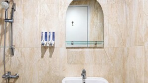 A bathroom with a shower, a sink, and a mirror above the mirror. - 2 Pax Comfy Studio At Tamansari Skylounge Makassar Apartment (Makassar)