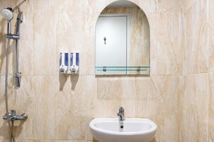 A bathroom with a shower, a sink, and a mirror above the mirror.