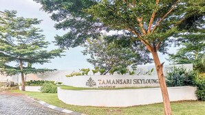 A sign for Tamansari Sky Lounge Apartments with a landscaped area and trees. - 2 Pax Comfy Studio At Tamansari Skylounge Makassar Apartment (Makassar)