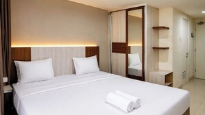 A hotel room with a large bed, a wardrobe, and a mirror. - 2 Pax Comfy Studio At Tamansari Skylounge Makassar Apartment (Makassar)