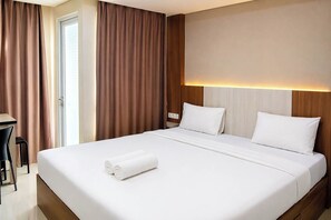 Quarto de hotel com uma cama grande, uma escrivaninha e uma cadeira.