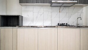 A kitchen with light wood cabinets, a marble backsplash, and a stainless steel range hood. - 2 Pax Comfy Studio At Tamansari Skylounge Makassar Apartment (Makassar)