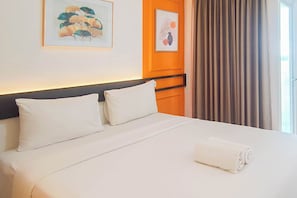 A neatly made bed with white linens, a rolled towel, and two pillows. - Practical Studio At Tamansari Skylounge Makassar Apartment (Makassar)