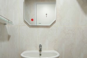 A bathroom with a white sink, a glass shelf, and a white cabinet with a lock. - Practical Studio At Tamansari Skylounge Makassar Apartment (Makassar)