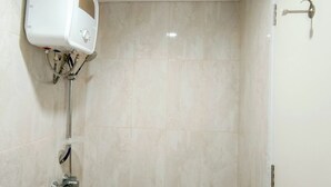 A bathroom with a white toilet, a shower with a chrome faucet, and a wall-mounted control panel.