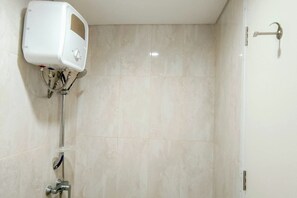 Un baño con inodoro blanco, ducha con grifo cromado y panel de control en la pared.