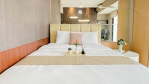 A modern hotel room with a large bed, a headboard, a bedside table with a vase, and a view of the room's interior. - 2 Pax Serene Studio At Tamansari Sudirman Apartment (Jakarta)
