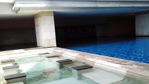 A swimming pool with clear water, stone steps leading into it, and a partially visible sign that reads 'MANSARI.' - 2 Pax Serene Studio At Tamansari Sudirman Apartment (Jakarta)