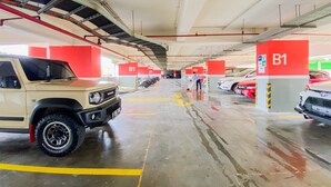 Un parking à plusieurs niveaux, avec de nombreux panneaux indiquant le niveau B1, un VUS beige et une voiture rouge.