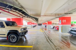 Un aparcamiento con varios carteles de nivel B1, un SUV beige y un coche rojo.