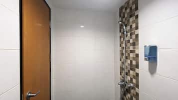 Un baño con azulejos blancos, una puerta de madera, una ducha con pared de baldosas de cuadros y un dispensador de jabón.