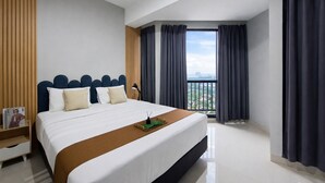 Quarto de hotel moderno com uma cama grande, uma mesa de cabeceira, uma janela com cortinas e vista para a cidade.