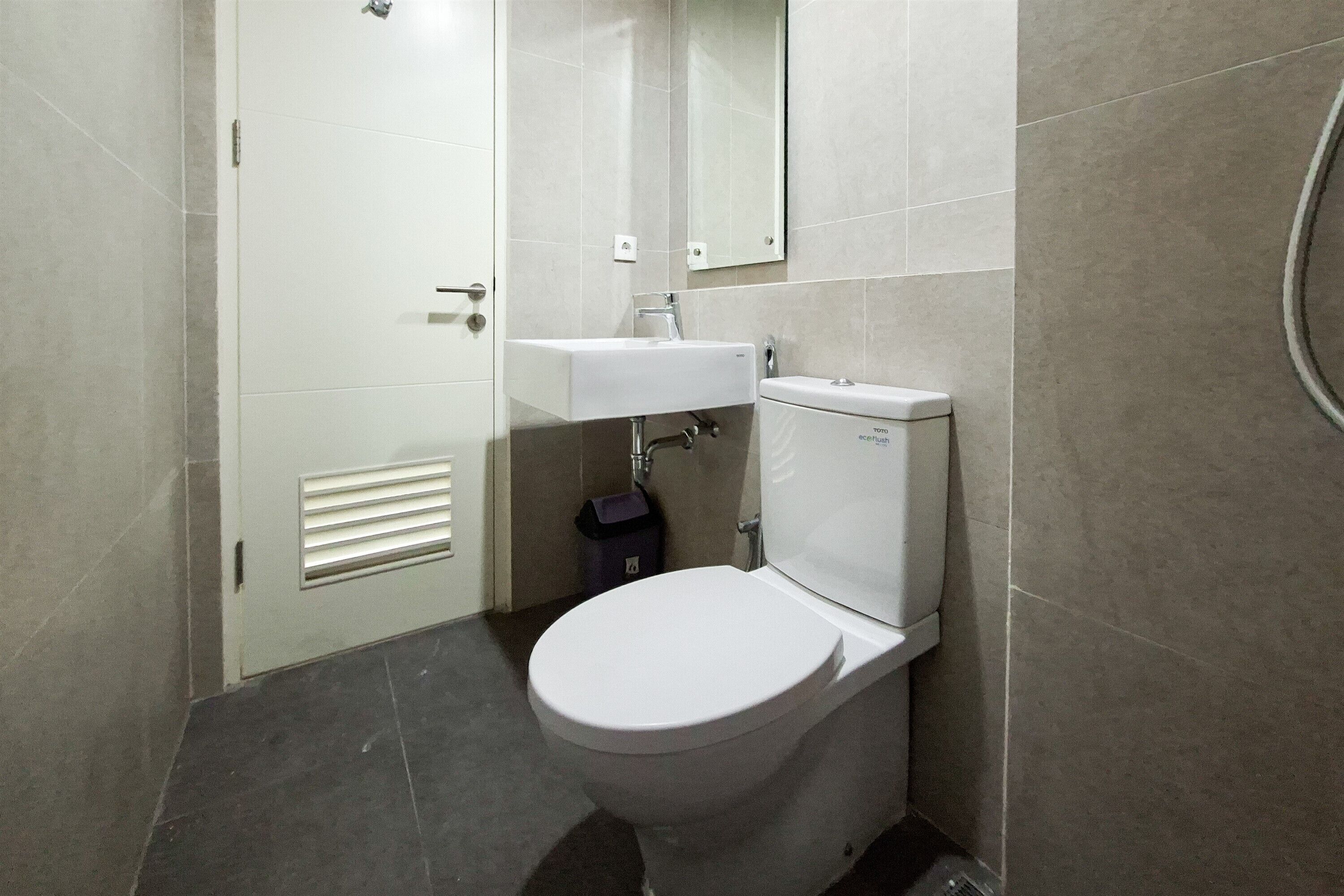 Un baño pequeño y moderno con inodoro, lavamanos y espejo.