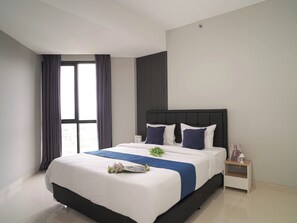 Una habitación de hotel moderna con una cama grande, una mesita de noche, una ventana con cortinas y vistas al exterior.