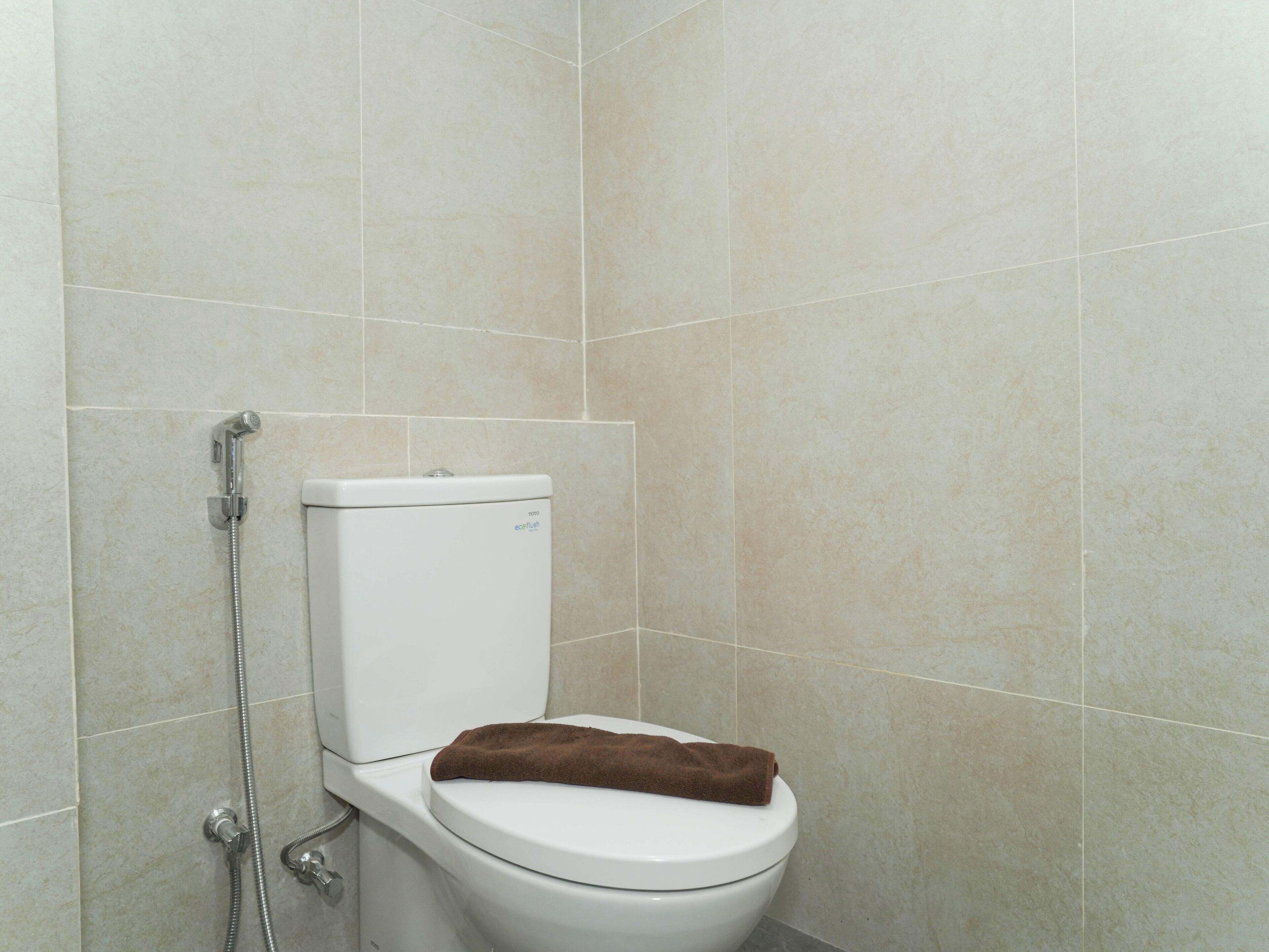 A bathroom with a toilet, a shower, and a towel on the toilet seat.