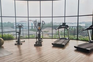A gym with exercise equipment and large windows. - Comfortable Classic Beige 1Br At Apartment The Ayoma (South Tangerang)