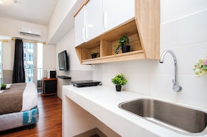 Una habitación de hotel moderna con kitchenette, una cama, televisión y vistas a la ciudad.