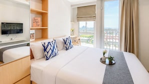 A hotel room with a bed, a TV, a city view, and a balcony. - Studio Room Apartment At Tokyo Riverside Pik 2 Near Nice (Teluknaga)