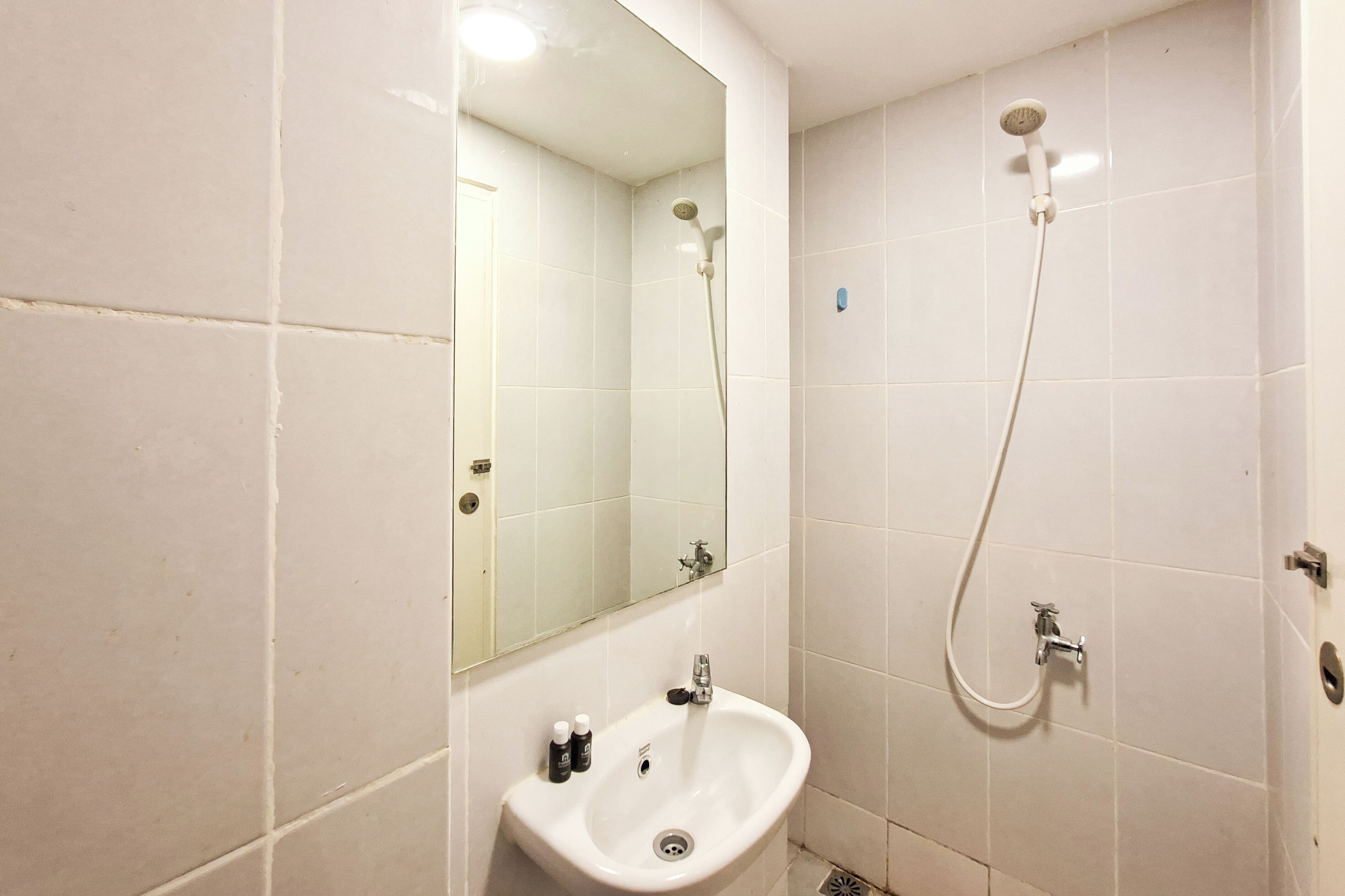 A bathroom with a white sink, a mirror, a shower, and a toilet.