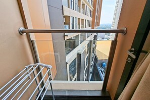 A balcony with a metal railing, a glass door, and a view of adjacent buildings. - Warm And Restful Studio Room At Apartment Transpark Bintaro (South Tangerang)