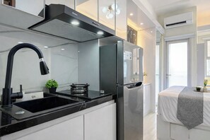 Eine moderne Küche mit einem schwarzen Wasserhahn, Edelstahlgeräten und einer Marmorarbeitsplatte.