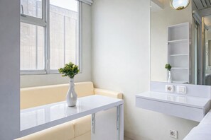 A modern bathroom with a white vanity, a mirror, and a window. - Comfy White Studio At Transpark Juanda Bekasi Timur Apartment (Bekasi)