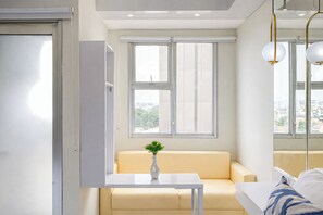 A modern room with a sofa, a small table, a vase with greenery, and a window with a view of buildings.