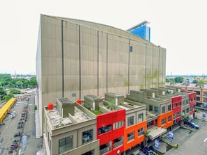 Ein mehrstöckiges Gebäude mit flacher Fassade, ein Parkplatz mit mehreren Fahrzeugen und freier Sicht auf die umliegende Stadtlandschaft.