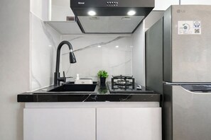 A modern kitchen with a black faucet, a gas stove, and a stainless steel refrigerator.