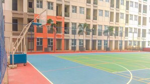 An indoor basketball court with a blue and red floor, surrounded by a fence, and adjacent to a multi-story building with balconies. - Airy Studio Apartment At Transpark Juanda Bekasi Timur (Bekasi)