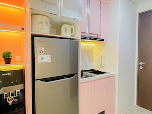 A compact kitchen with a refrigerator, a coffee machine, a sink, and a water dispenser. - Airy Studio Apartment At Transpark Juanda Bekasi Timur (Bekasi)