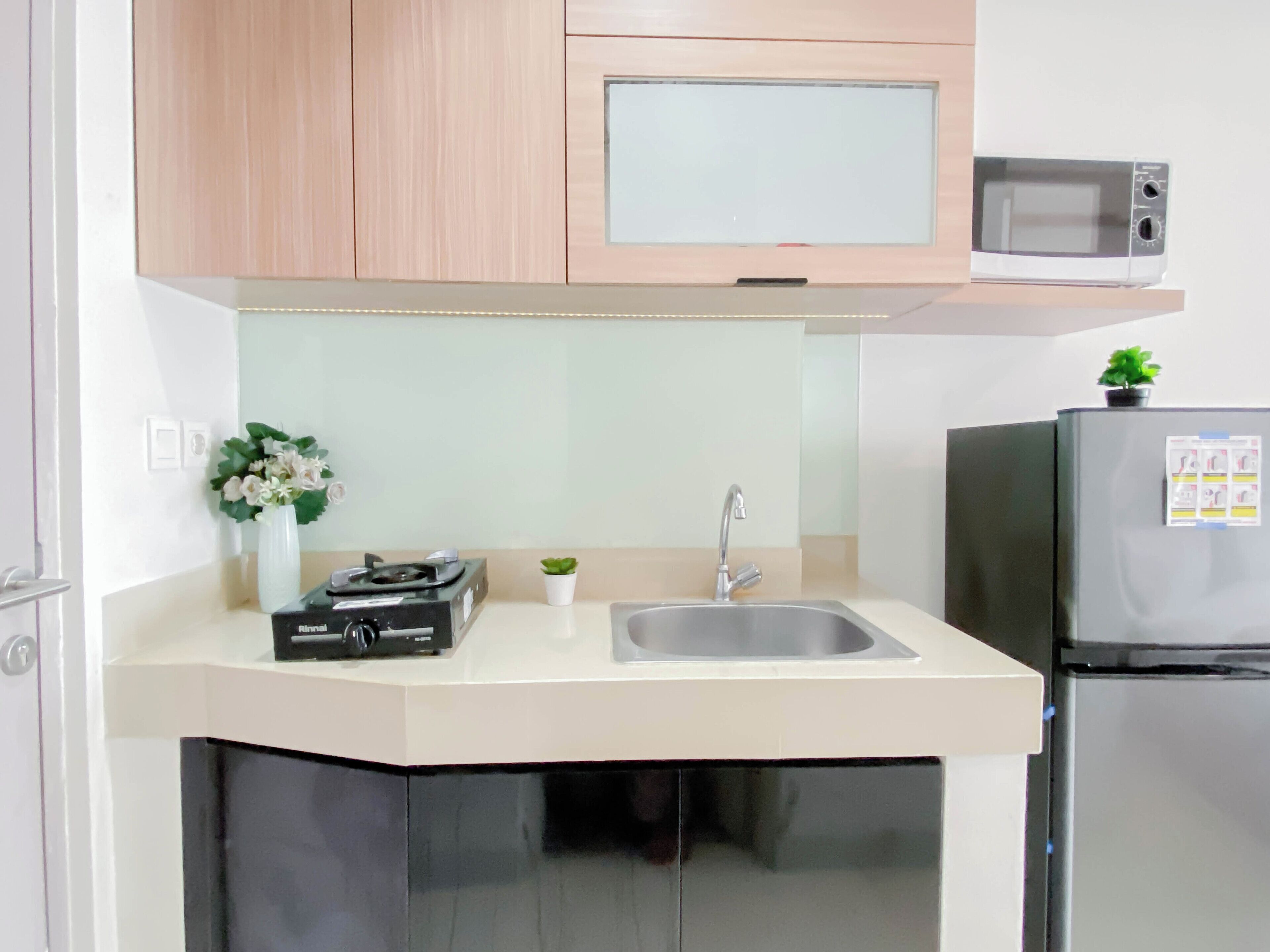 A kitchen with a microwave, sink, and a small potted plant.