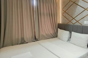 A hotel room with a bed, curtains, a headboard, and a wall with a geometric pattern. - Functional And Cozy 2Br Apartment At Vida View Makassar (Makassar)