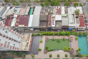 Vista aèria d'una zona comercial amb edificis, un aparcament i un pati ajardinat amb piscina.