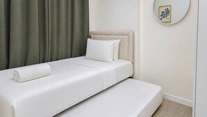 A single bed with a white mattress, a rolled white towel, and a pillow. - Cozy Living 2Br At Vida View Makassar Apartment (Makassar)